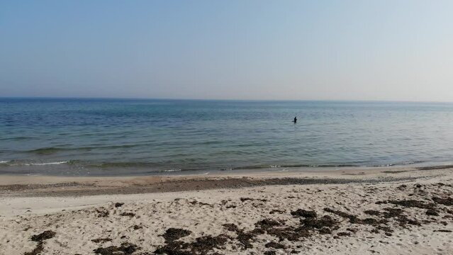 Luftaufnahme von Angler mit Angel in Wathose im Wasser bei Sonne watend per Drohne gefilmt als Schwenk
