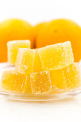 Orange marmalade candy and oranges fruits on a white wooden table.