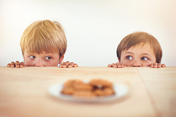 Who can resist a cookie. Two little boys sneakily trying to take a cookie from a plate. - obrazy, fototapety, plakaty