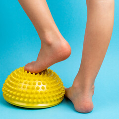 children's feet with a yellow balancer on a light blue background, treatment and prevention of flat...