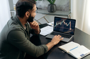 Fototapeta na wymiar Laptop screen with stock diagrams. Crypto trader investor broker using laptop for cryptocurrency financial market analysis, buying or selling cryptocurrency, planning strategy