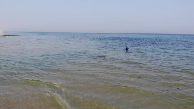 Luftaufnahme von Angler mit Angel in Wathose im Wasser bei Sonne watend per Drohne gefilmt als Schwenk
