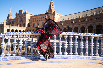 Fototapeta premium Young and beautiful woman dancing flamenco and Spanish posing in urban clothes, wearing her hair loose and long and standing on the tips of her shoes. flamenco cultural heritage of humanity.