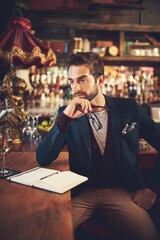 Working on his latest book. Cropped shot of a young man sitting with his journal in a bar.