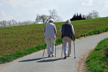 zwei seniorinnen gehen an nordic-walking-stöcken