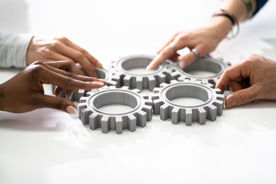Group Of Businesspeople Joining Together Gears On Table