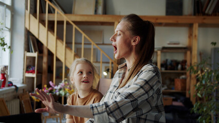 The girl sings with her mother. They play the piano and have fun