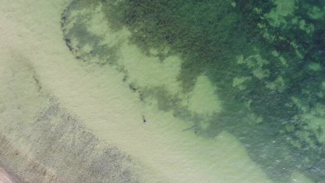 Luftaufnahme von Angler mit Angel in Wathose im Wasser bei Sonne watend per Drohne gefilmt von oben