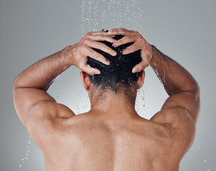 Time for a relaxing shower. Shot of an unrecognizable man washing his hair in the shower against a grey background.