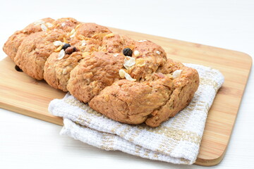 Healthy wholemeal big bread, with cereals, raisins, peanuts and honey on white wooden background
