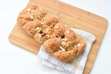 Healthy wholemeal big bread, with cereals, raisins, peanuts and honey on white wooden background
