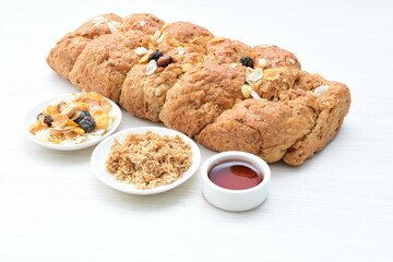 Healthy wholemeal big bread, with cereals, raisins, peanuts and honey on white wooden background