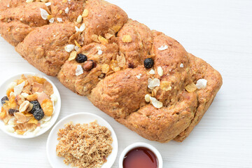 Healthy wholemeal big bread, with cereals, raisins, peanuts and honey on white wooden background
