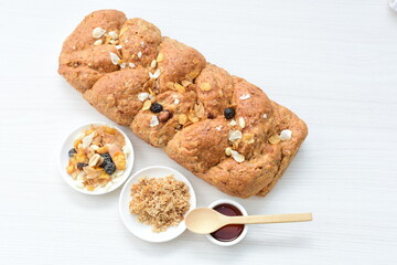 Healthy wholemeal big bread, with cereals, raisins, peanuts and honey on white wooden background