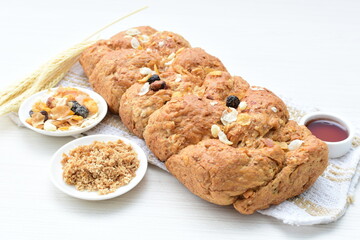Healthy wholemeal big bread, with cereals, raisins, peanuts and honey on white wooden background