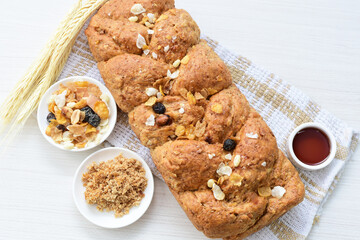 Healthy wholemeal big bread, with cereals, raisins, peanuts and honey on white wooden background