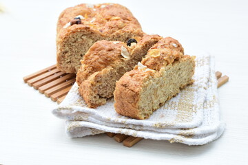 Healthy wholemeal big bread, with cereals, raisins, peanuts and honey on white wooden background