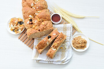 Healthy wholemeal big bread, with cereals, raisins, peanuts and honey on white wooden background