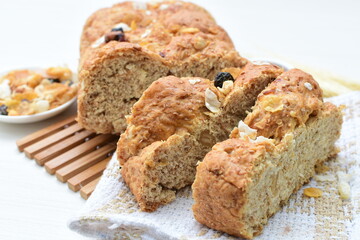 Healthy wholemeal big bread, with cereals, raisins, peanuts and honey on white wooden background