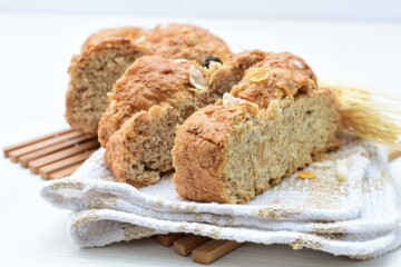 Healthy wholemeal big bread, with cereals, raisins, peanuts and honey on white wooden background