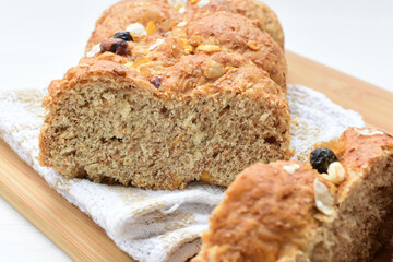 Healthy wholemeal big bread, with cereals, raisins, peanuts and honey on white wooden background