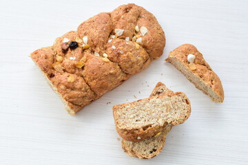 Healthy wholemeal big bread, with cereals, raisins, peanuts and honey on white wooden background