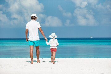 Happy father and his adorable little daughter at tropical beach walking together