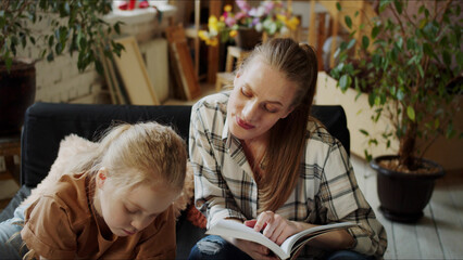 A woman studies what a child is drawing and looks in her notebook