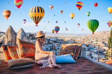 Happy young woman during sunrise watching hot air balloons in Cappadocia, Turkey