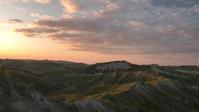 Time lapse at sunset on badlands and hills with moving colored clouds, Emilia Romagna, Italy