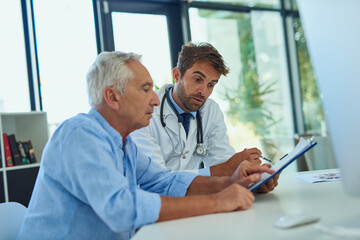 Working together to get him back to the best health. Shot of a handsome doctor going over some paperwork with a male senior patient in a clinic.