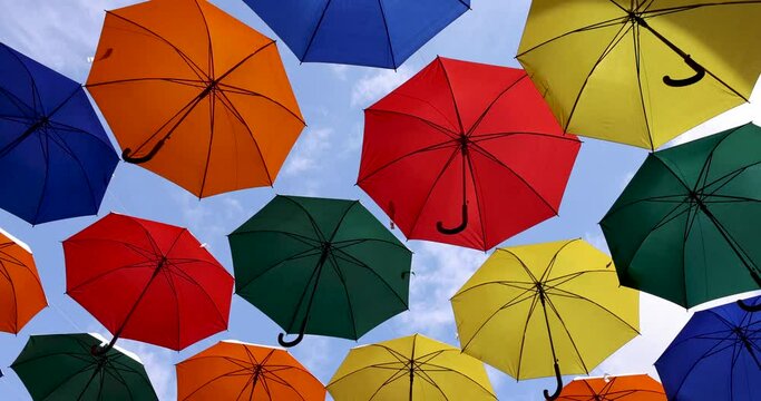 colorful umbrellas hanging against blue sky background. city street art