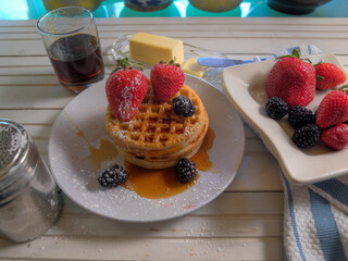 Top view of whole grain waffles and fruit on white natural table.