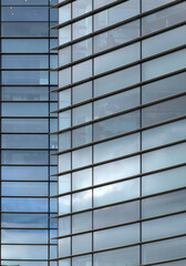 full frame modern office architecture abstract with geometric shapes of tall buildings reflecting the blue cloudy sky in large glass windows