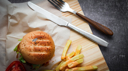 Home made hamburgers served with french fries and tomatoes on a wooden table. Fast food and junk food.
