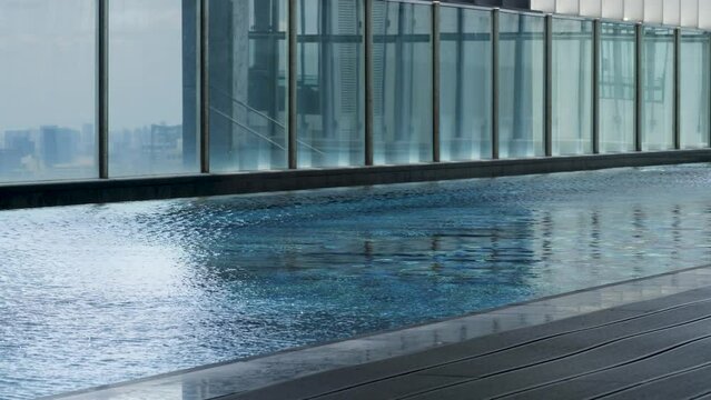 Swimming pool on roof of skyscraper. Blue and white tiles background. Vacation or holiday. Clear ripple transparent water