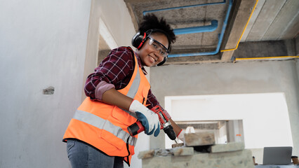 Cute looking female engineer with afro hairstyle. African descent  cordless electric drill screws...
