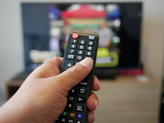 closeup of hand with the remote control television and presses the button.	
