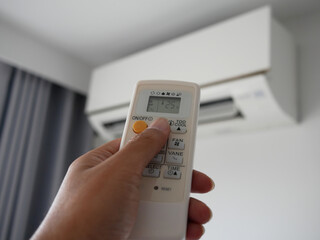 closeup of hand adjust remote control air conditioner.	