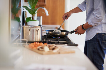 Cooking up something delicious. Shot of an unrecognizable man cooking in the kitchen at home.