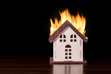 Obraz na płótnie Canvas Model house in fire on black background with copy space.