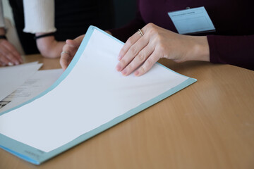 Consultation d'un dossier au bureau, mains d'une femme sur un dossier avec zone d'écriture vierge