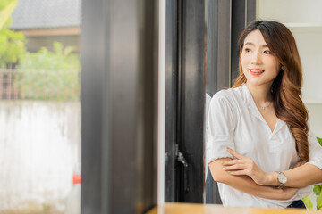 Portrait of a beautiful woman smiling and standing at the window, office business concept, working and looking outside. smile and think for the future