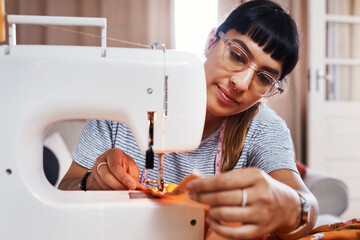 I just love seeing people in my beautiful creations. Cropped shot of a young woman stitching fabric using a sewing machine at home.
