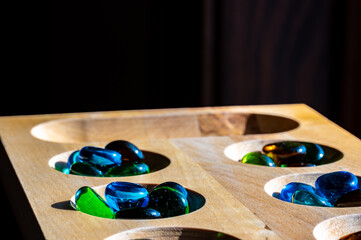 Obraz na płótnie Canvas Selective focus on glass beads on a wooden mancala board