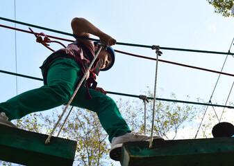 A boy in a helmet in an extreme park. Climbing in the rope park.