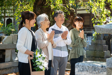 お墓参りに来た家族（合掌・笑顔）
