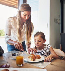 Let me help you with that, my angel. Shot of a mother having breakfast with her little daughter at home.