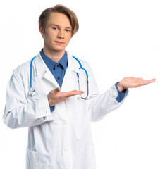 Fototapeta premium portrait of a student, teenager, young professional. a guy in a medical gown looks at us and points to the side. place for an inscription or product.