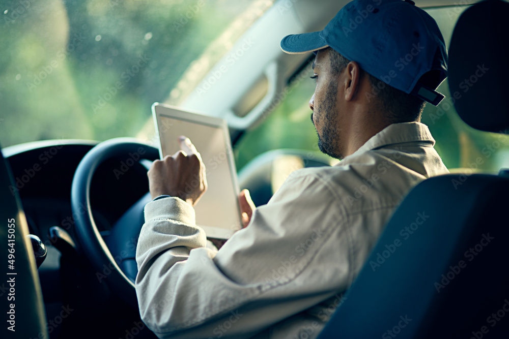 Aufkleber Logging his next delivery. Cropped shot of a delivery man using a digital tablet while sitting in his van.